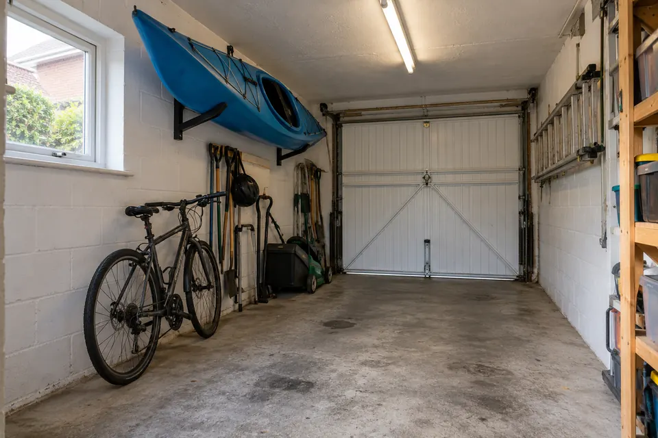 The garage before it became a home office: bare block walls, concrete floor, bikes and a kayak on the wall (design visualisation)